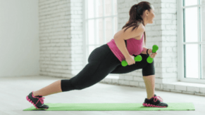 Neskak ariketa bat egiten du dumbbells-ekin